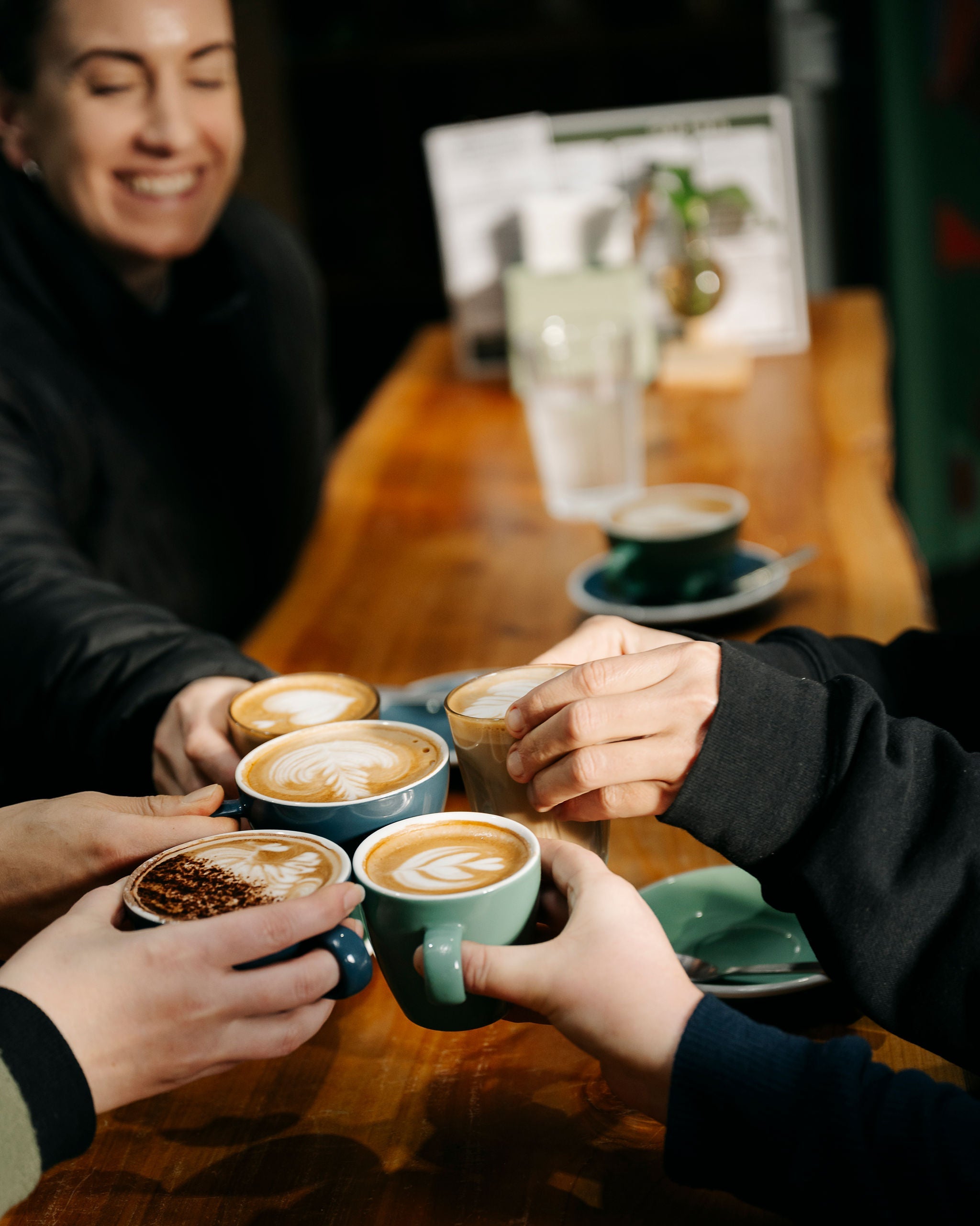 People enjoying coffee at a table with various cups and a magazine in the background.