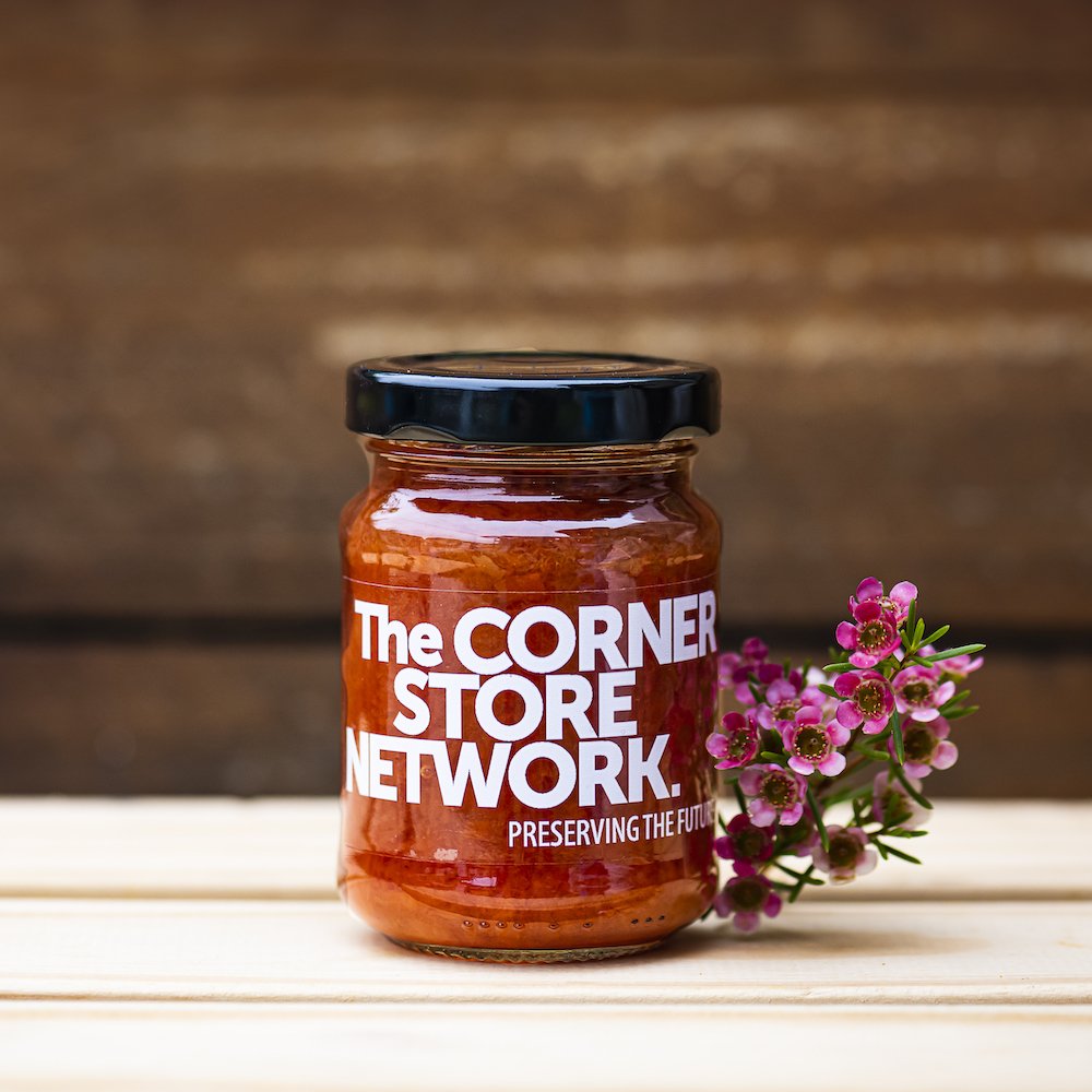 jar of chilli jam made from donated chillies on timber box next to flower