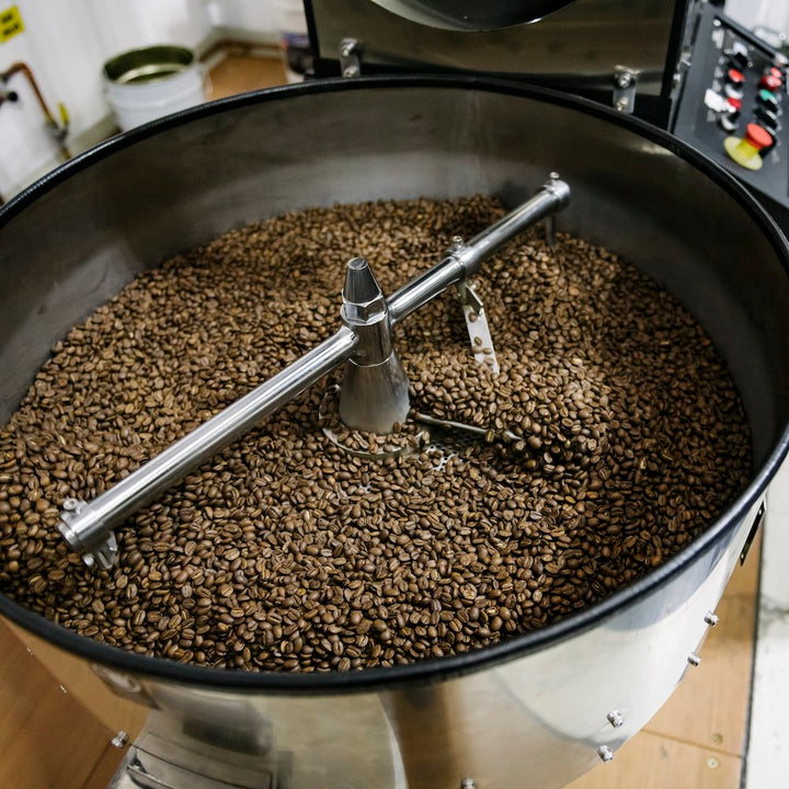 freshly roasted coffee beans sitting in silver roaster