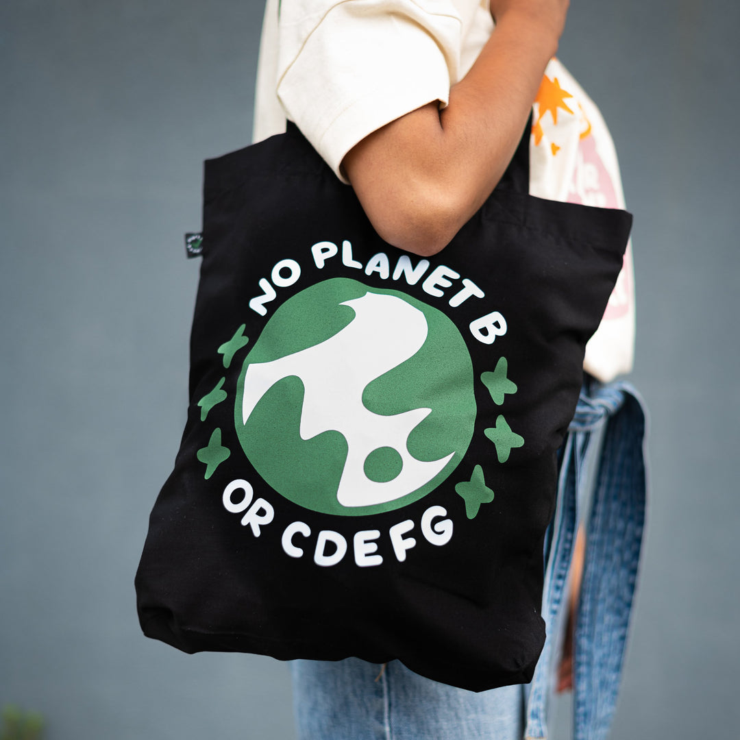 arm holding organic black cotton tote with blue and green design saying no planet b or cdefg surrounding planet earth
