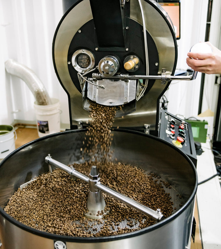 brown coffee beans pouring out of coffee roasting machine