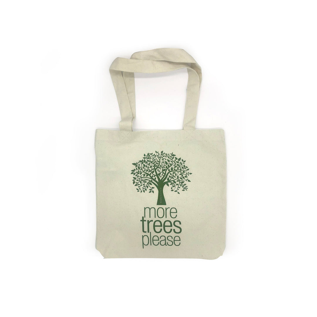white tote bag made from recycled materials featuring illustrated green tree with the words more trees please underneath
