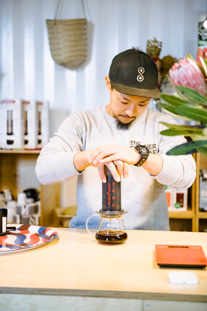 barista pushing down on an aeropress into a glass jug in a cafe
