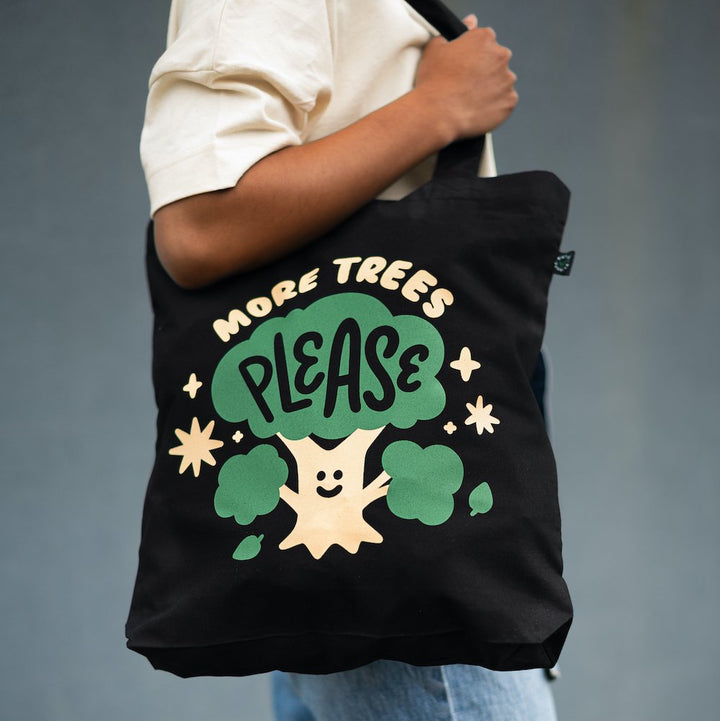 organic black cotton tote with cream and green design showing a smiling tree with words more trees please