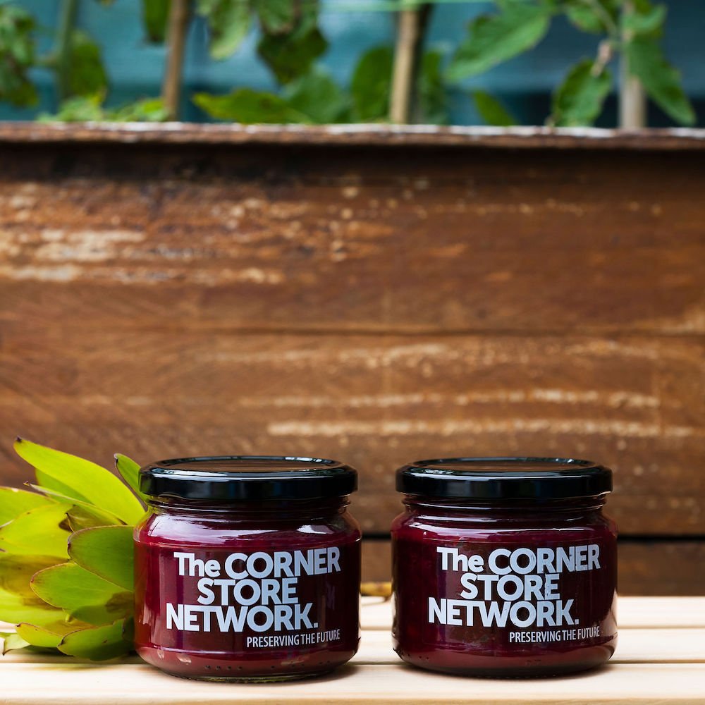two jars of beetroot relish made from donated beetroot on timber box next to flower