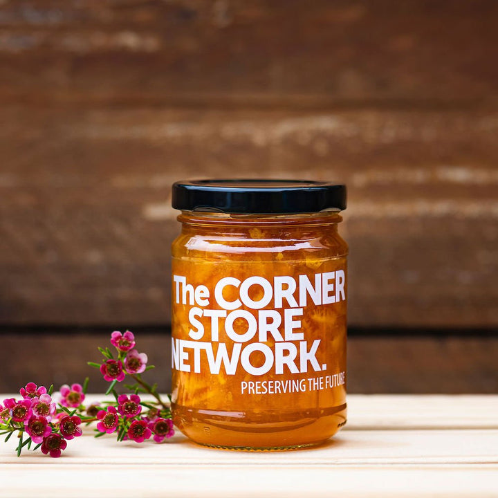 jar of ORANGE MARMALADE made from donated fruit on timber box next to flower